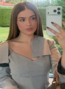 Sophie, Brazilian escort in London, taking a mirror selfie in a grey dress