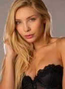 Elara, high class Brazilian escort in London, with long blonde hair in a black lace bustier